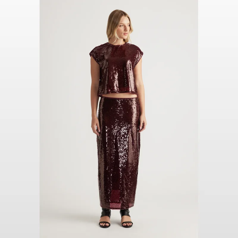 Woman wearing a burgundy sequin shell top with short sleeves and a round neckline.