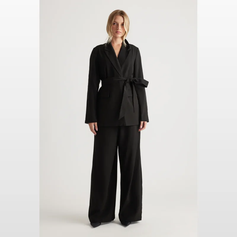 Woman wearing a black Decjuba Elena Organza Back Blazer with a tie waist and matching wide-leg trousers.