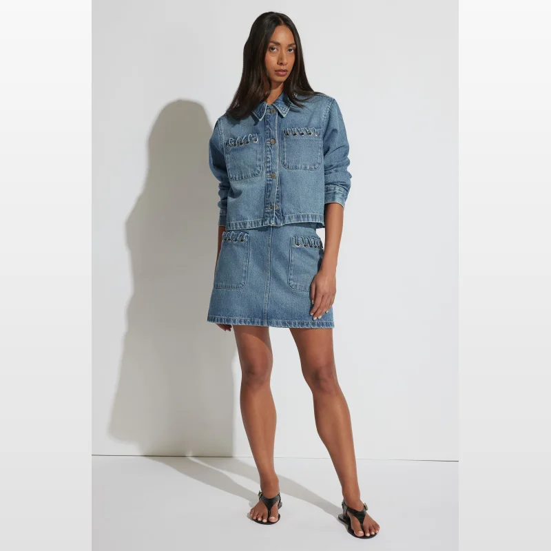 Woman wearing a blue denim skirt with patch pockets and whip stitch detailing.