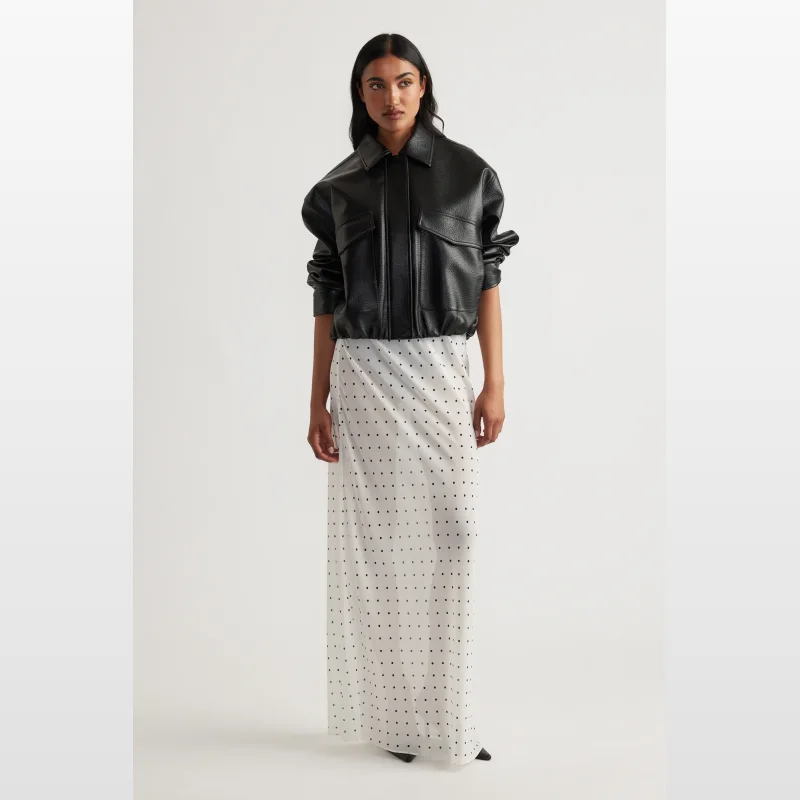 Model wearing a white sheer maxi skirt with black polka dots and an elasticated waistband.