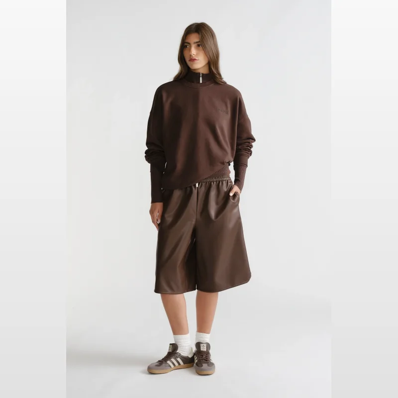 Woman wearing a brown Decjuba D-Luxe washed terry sweatshirt with a crew neckline and rubberised branding on the chest.