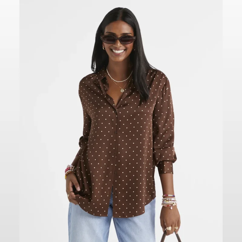 Woman wearing a brown satin shirt with white polka dots, sunglasses, and light blue jeans.