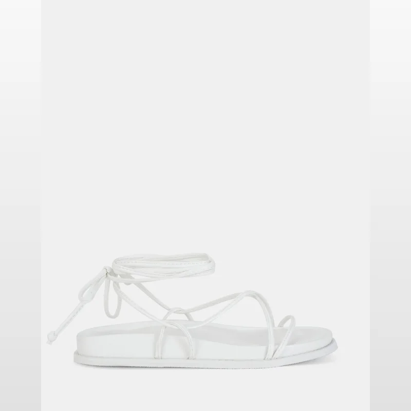 White TEELS strappy platform sandals with lace-up tubular straps and a round open-toe design.