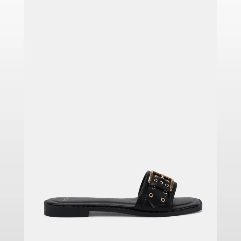 A single black slide sandal with a large gold buckle and grommet detailing, from the brand Novoshoes.
