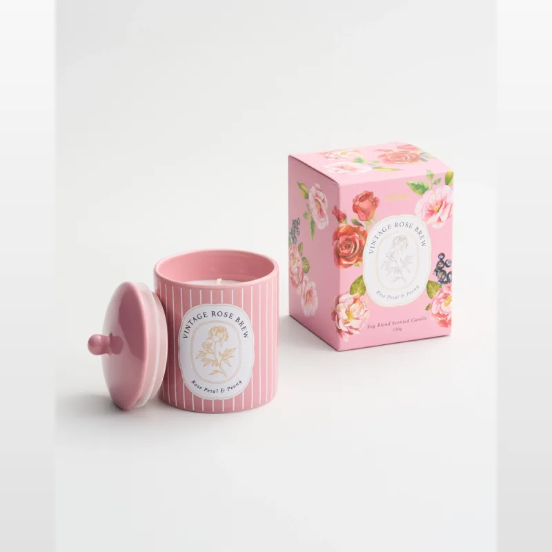 A pink ceramic candle with a lid, labelled 'Vintage Rose Brew', next to its matching pink floral patterned box. The candle is a soy blend scented candle weighing 150g.