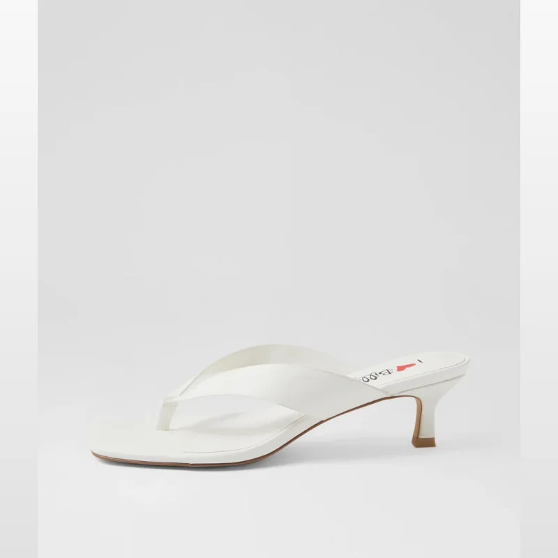 Close-up of a white Cerson sandal with a square toe and a low kitten heel, featuring a thong strap.