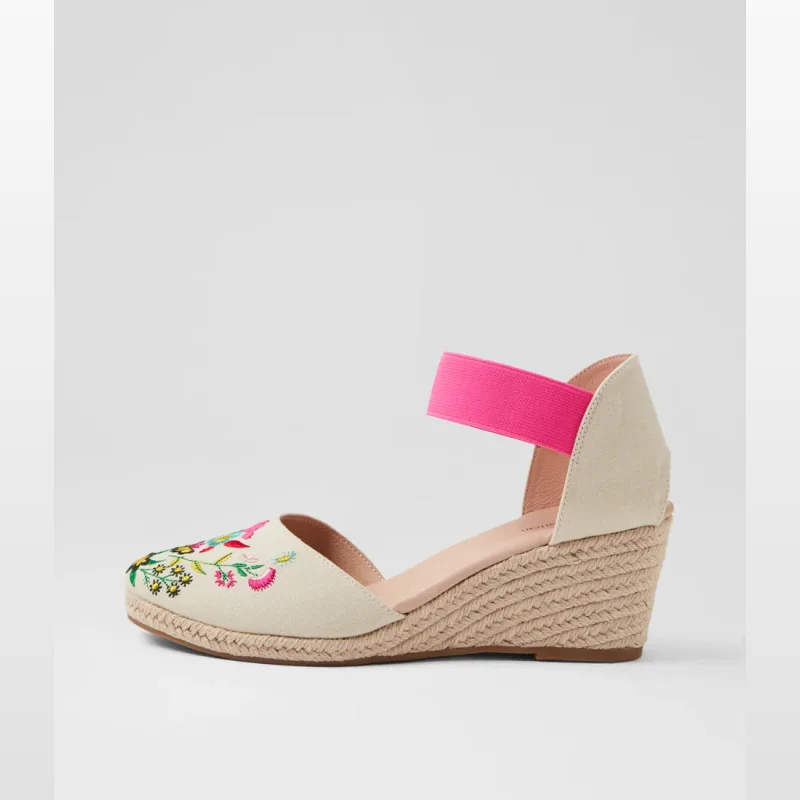 Side view of a beige espadrille wedge sandal with floral embroidery on the toe and a bright pink elastic ankle strap.