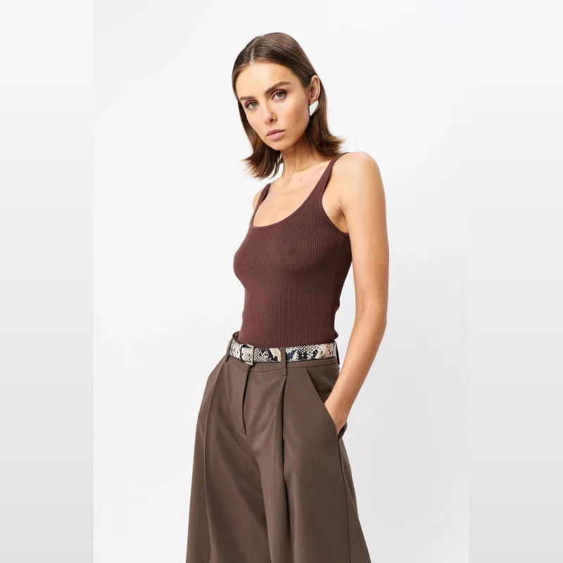 Woman wearing a brown ribbed knit tank top with thin straps and a scoop neckline, paired with brown trousers and a snakeskin belt.