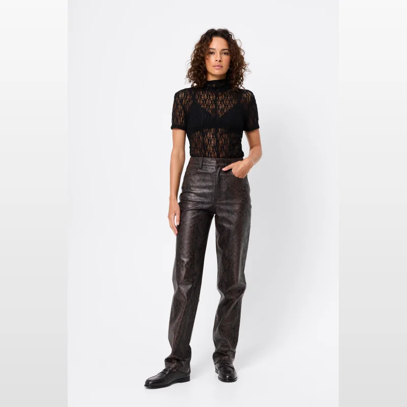 Woman wearing a black sheer spiderweb lace bodysuit with a grown-on neck and cap sleeves, paired with brown snake-print trousers.