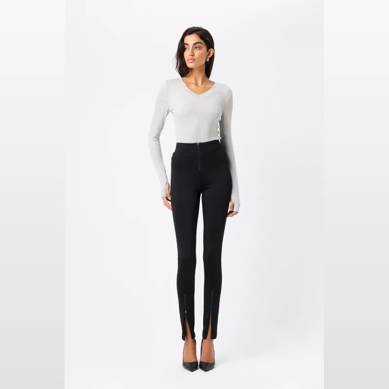 Woman wearing Mossman The Defensive Pant in black, featuring a form-fitting silhouette with zip detailing at the centre front and ankles.