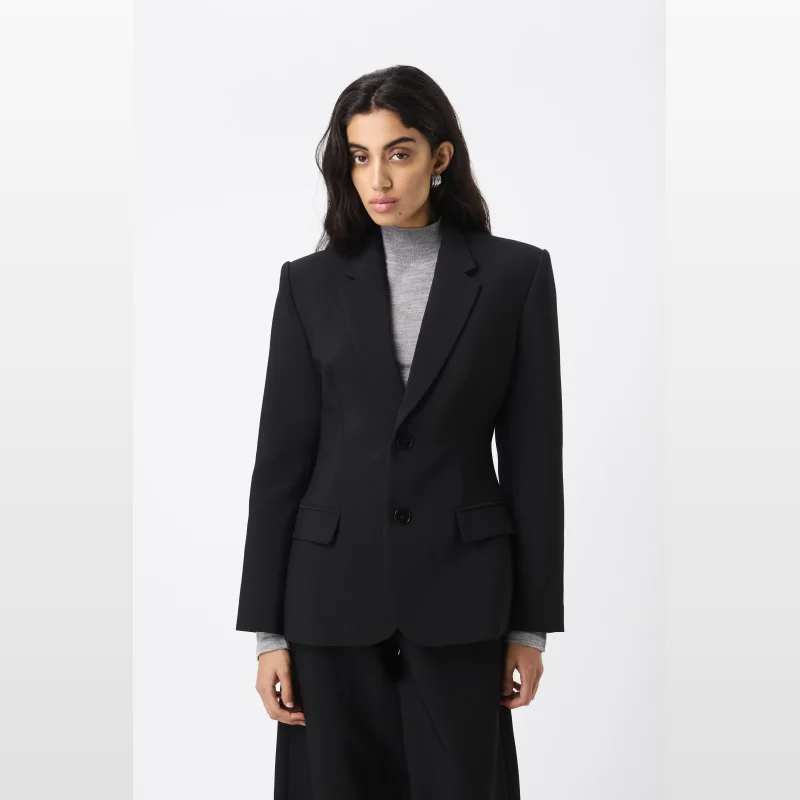 Woman wearing a black Mossman Sonder Blazer with a grey turtleneck.