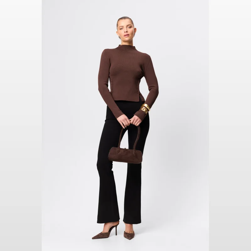 Model wearing Mossman Kennedy black flared tailored pants and a brown mock neck top, holding a brown handbag.
