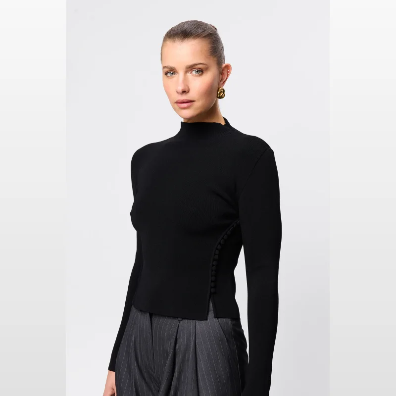 Model wearing a black Mossman Windsor Knit Top with a mock neckline and button detailing on the sleeves and sides.
